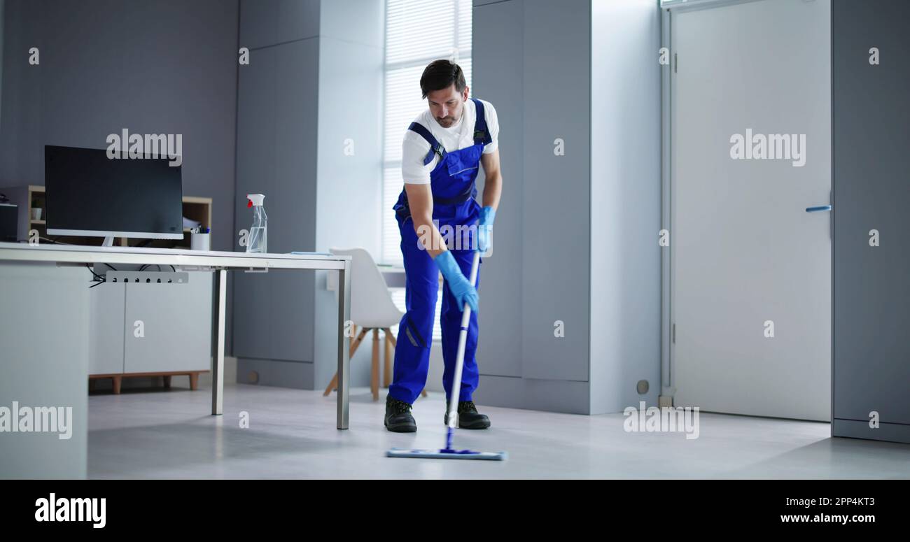 Portrait Of Happy Male Janitor Cleaning Floor At Office Stock Photo