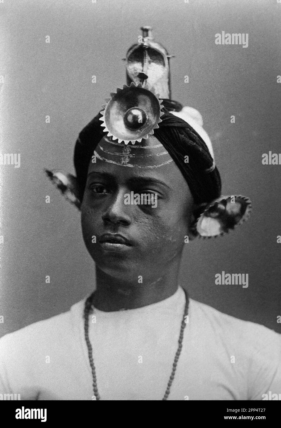 A young Indian man, wearing an elaborate headress and makeup, in a