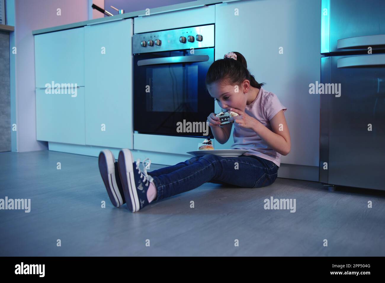 Child Eating Cake At Night Near Refrigerator Stock Photo Alamy