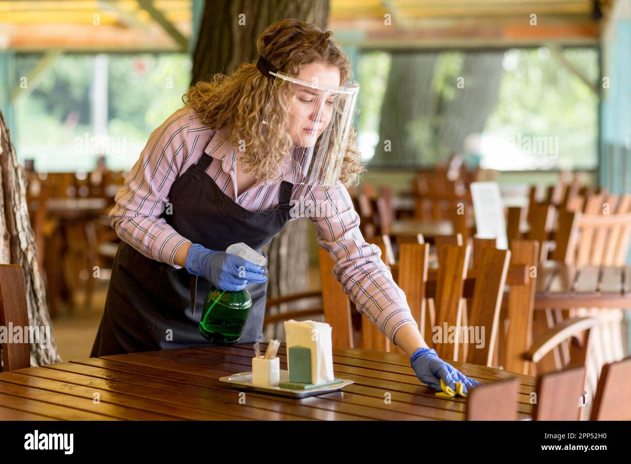 Woman with face protection cleaning tables Stock Photo