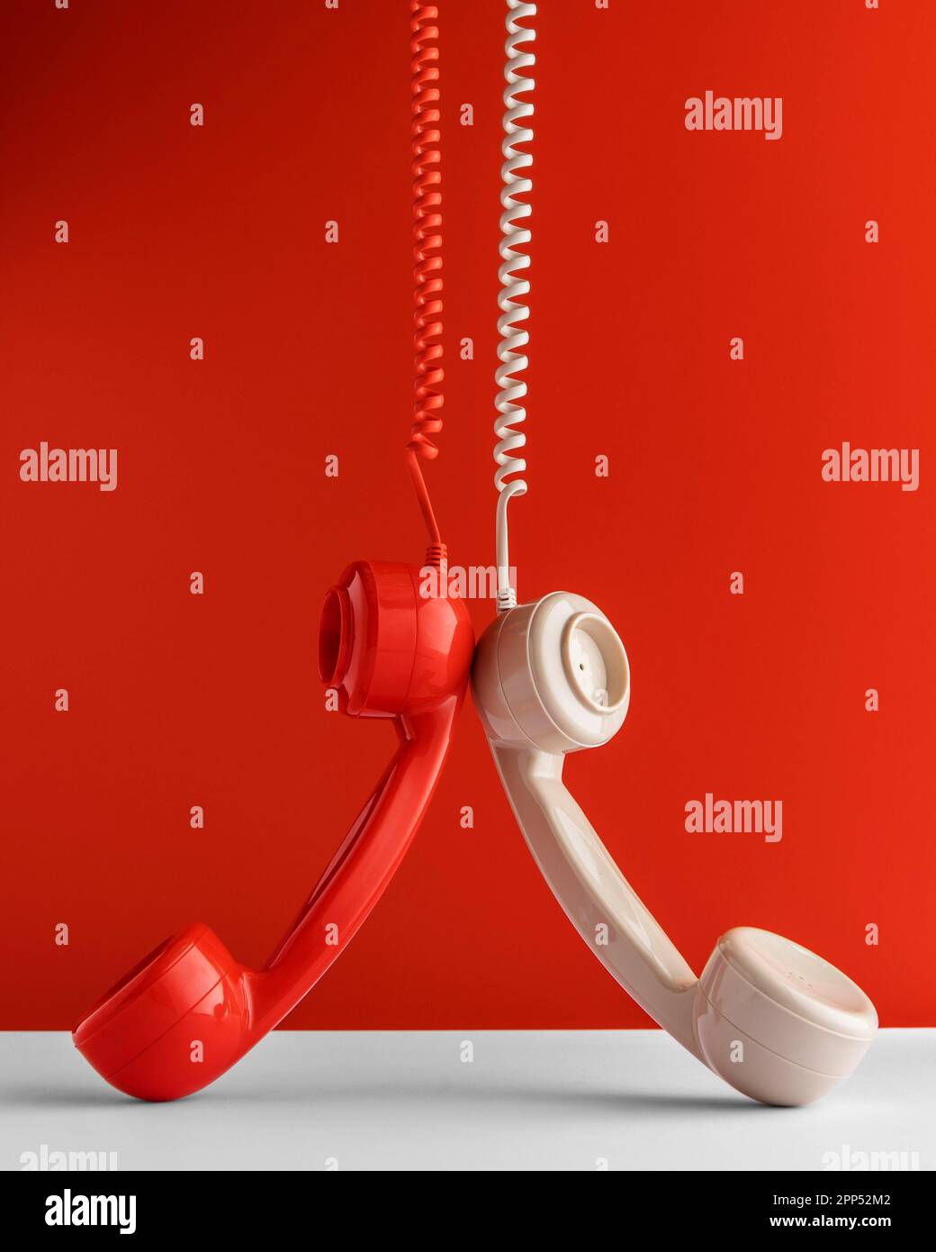 Front view two telephone receivers hanging from cord Stock Photo Alamy