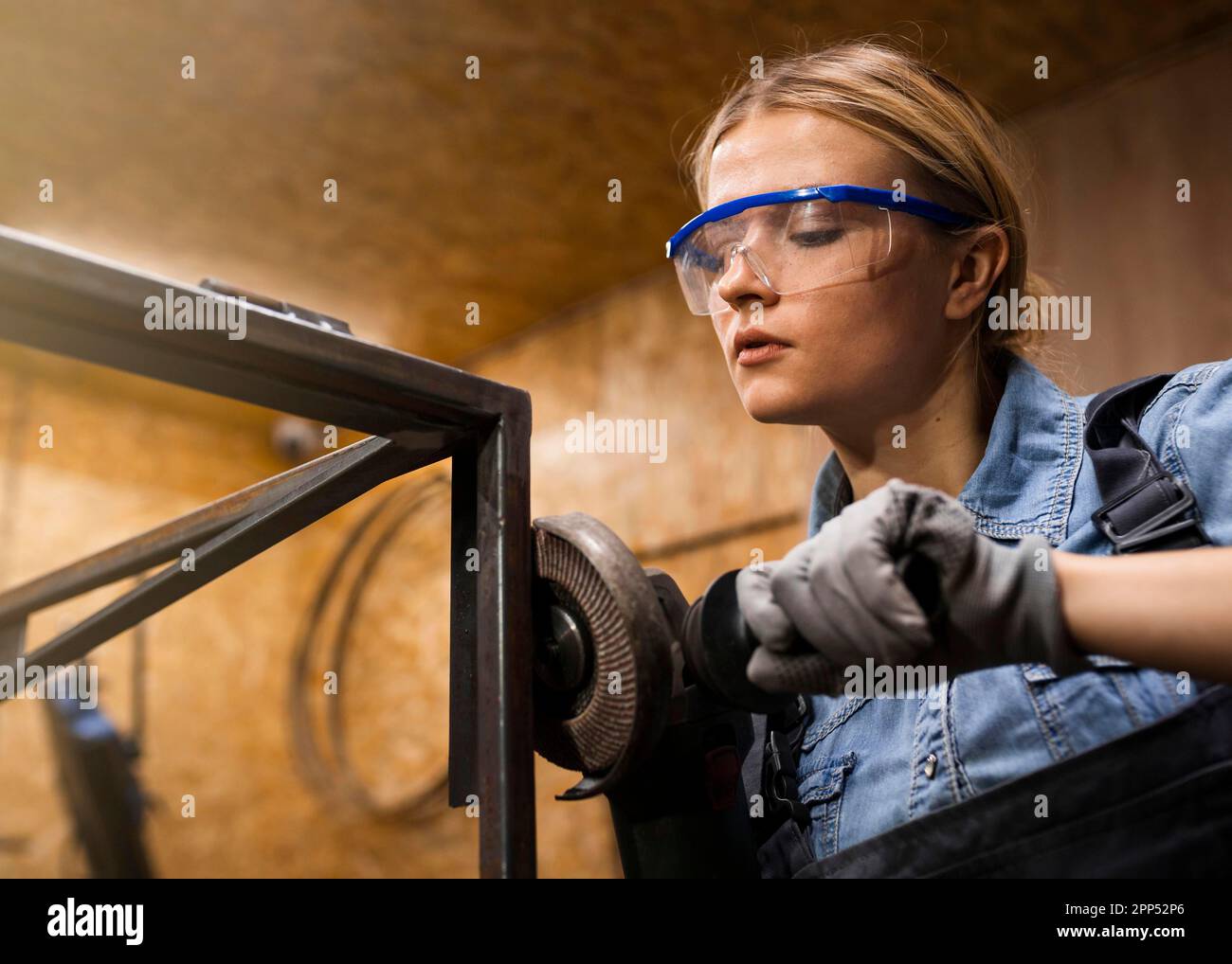 Female welder using angle grinder Stock Photo