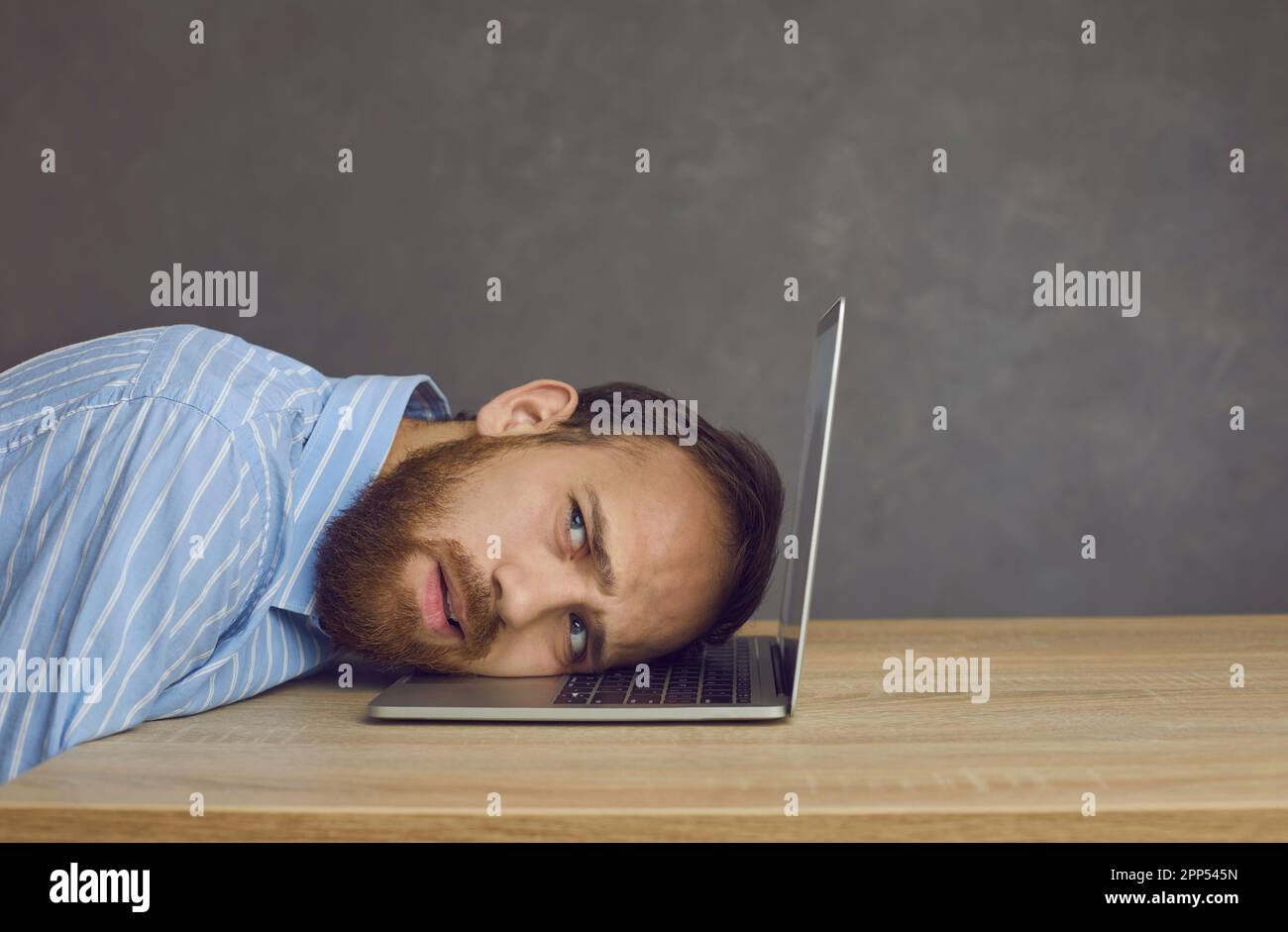 Business man freelancer lying on laptop keyboard with tired grimace on face Stock Photo