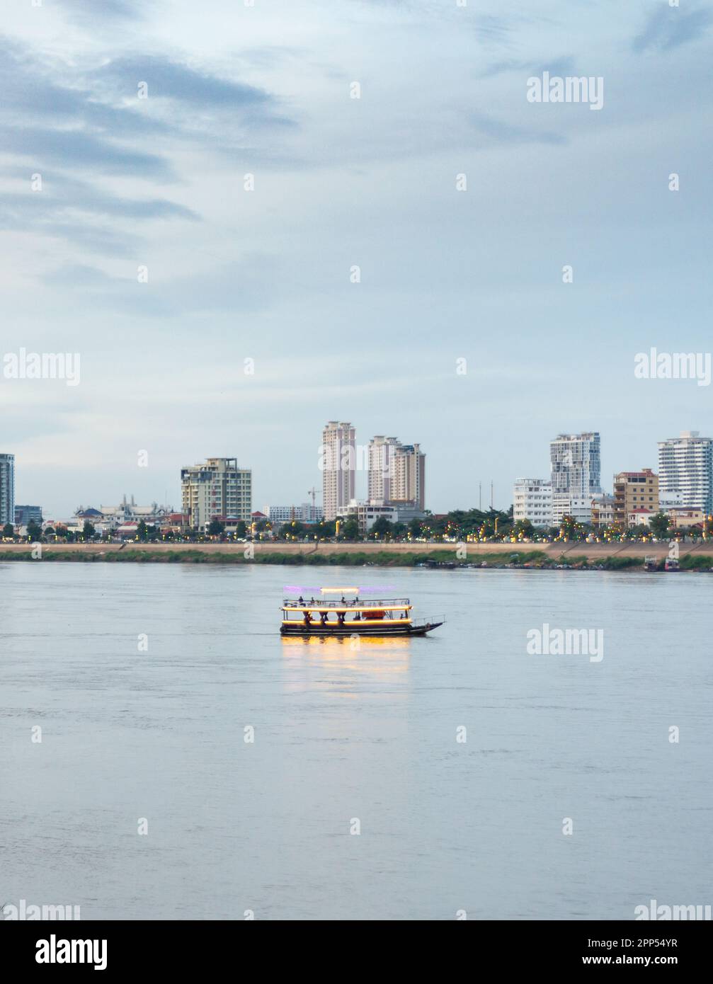 Lit up,carrying tourists up and down,to see Cambodia's capital city landmarks and the Mekong River,the sun has set,it is blue hour before dark,low tid Stock Photo