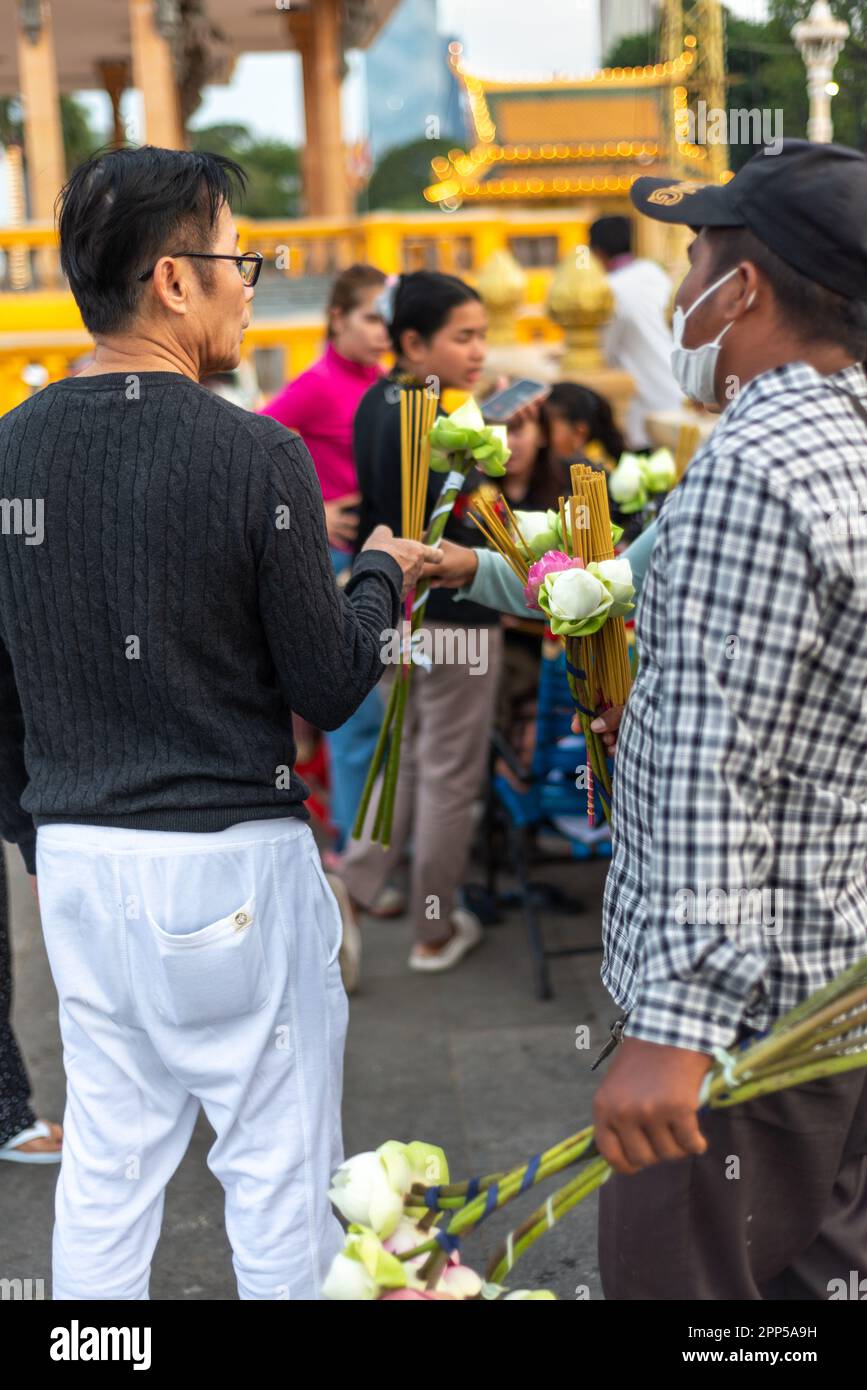 Phnom Penh,Cambodia-January 4th 2023: On a busy early evening at the holy shrine of Preah Ang Dorngkeu,men negotiate the purchse of items to use as of Stock Photo