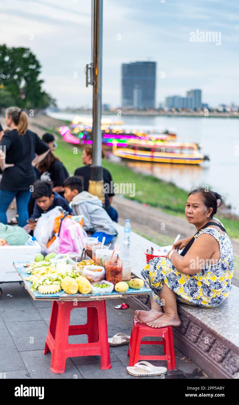 Phnom Penh,Cambodia-January 4th 2023: Food vedors wait for passing trade,while socializing,as the relative cool of the day arrives,after sunset. Stock Photo