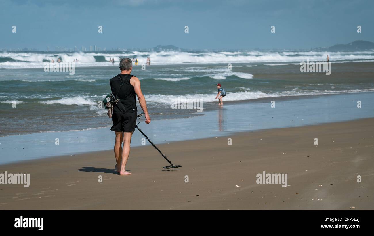 Gold Coast, Australia Man using a metal detector to find valuables on the beach Stock Photo