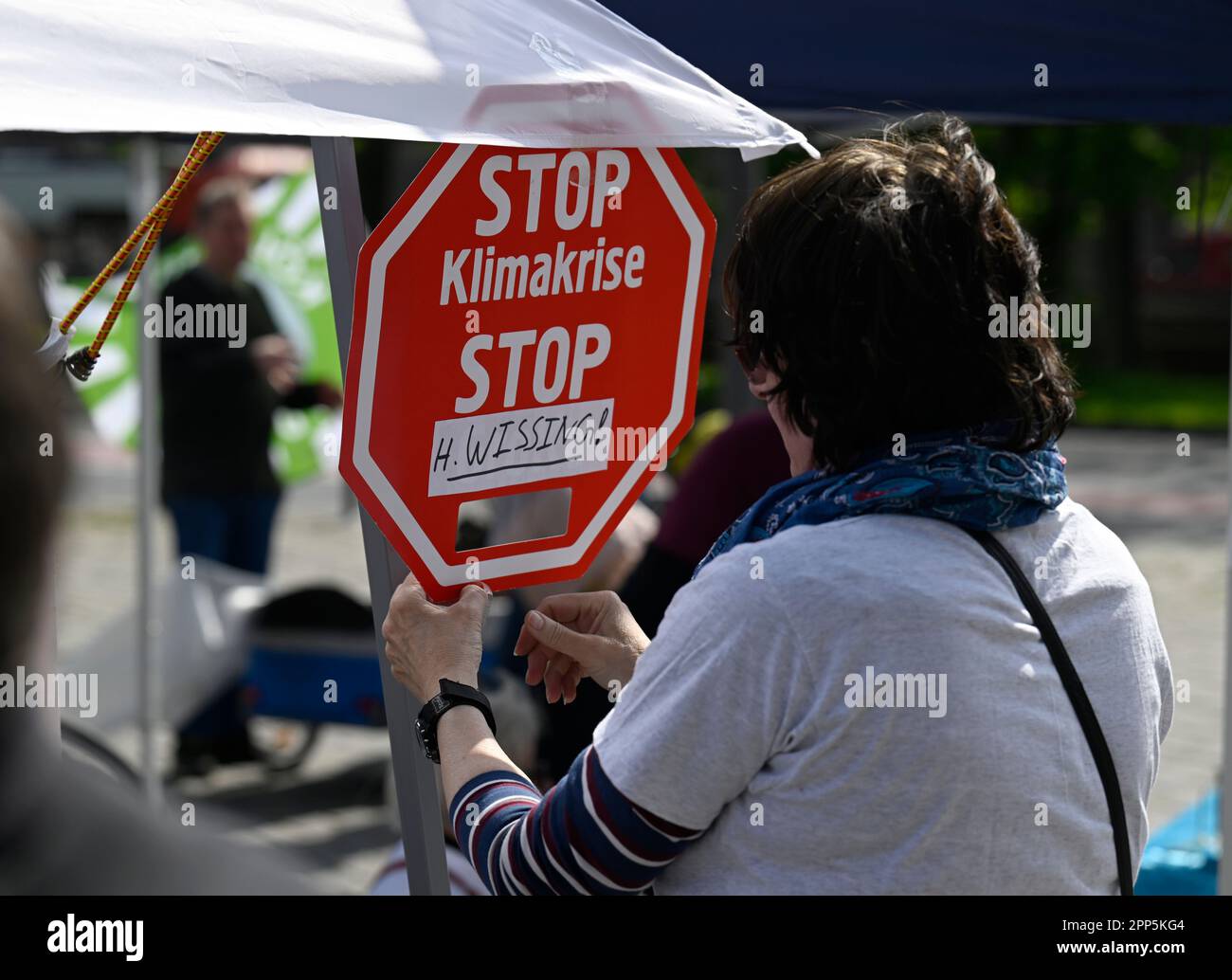 Cologne, Germany. 22nd Apr, 2023. A woman attaches a sign to a pavilion. Today, environmental initiatives are calling for nationwide days of action under the slogan 'Mobility turnaround now! Here in Cologne against the expansion of the A4. Credit: Roberto Pfeil/dpa/Alamy Live News Stock Photo