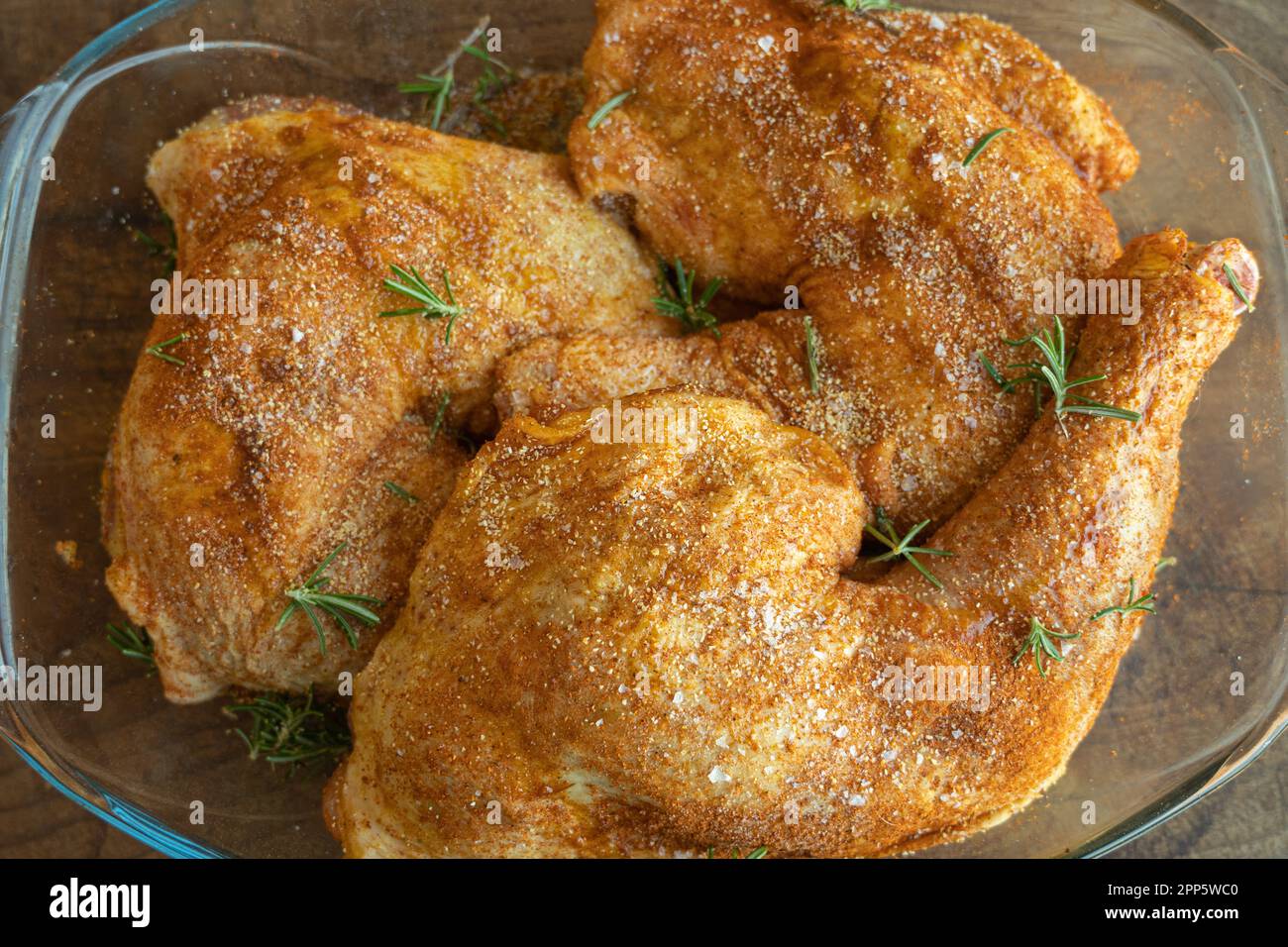 Marinated chicken tights with salt, black pepper, rosemary and paprika ready to be cooked Stock Photo