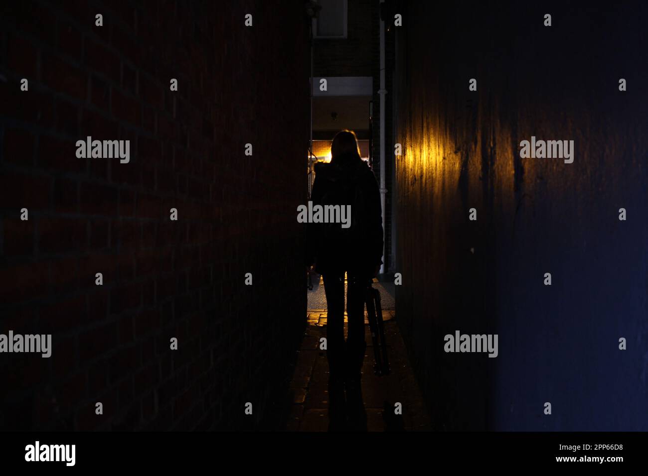 Woman in a dark alleyway at night Stock Photo