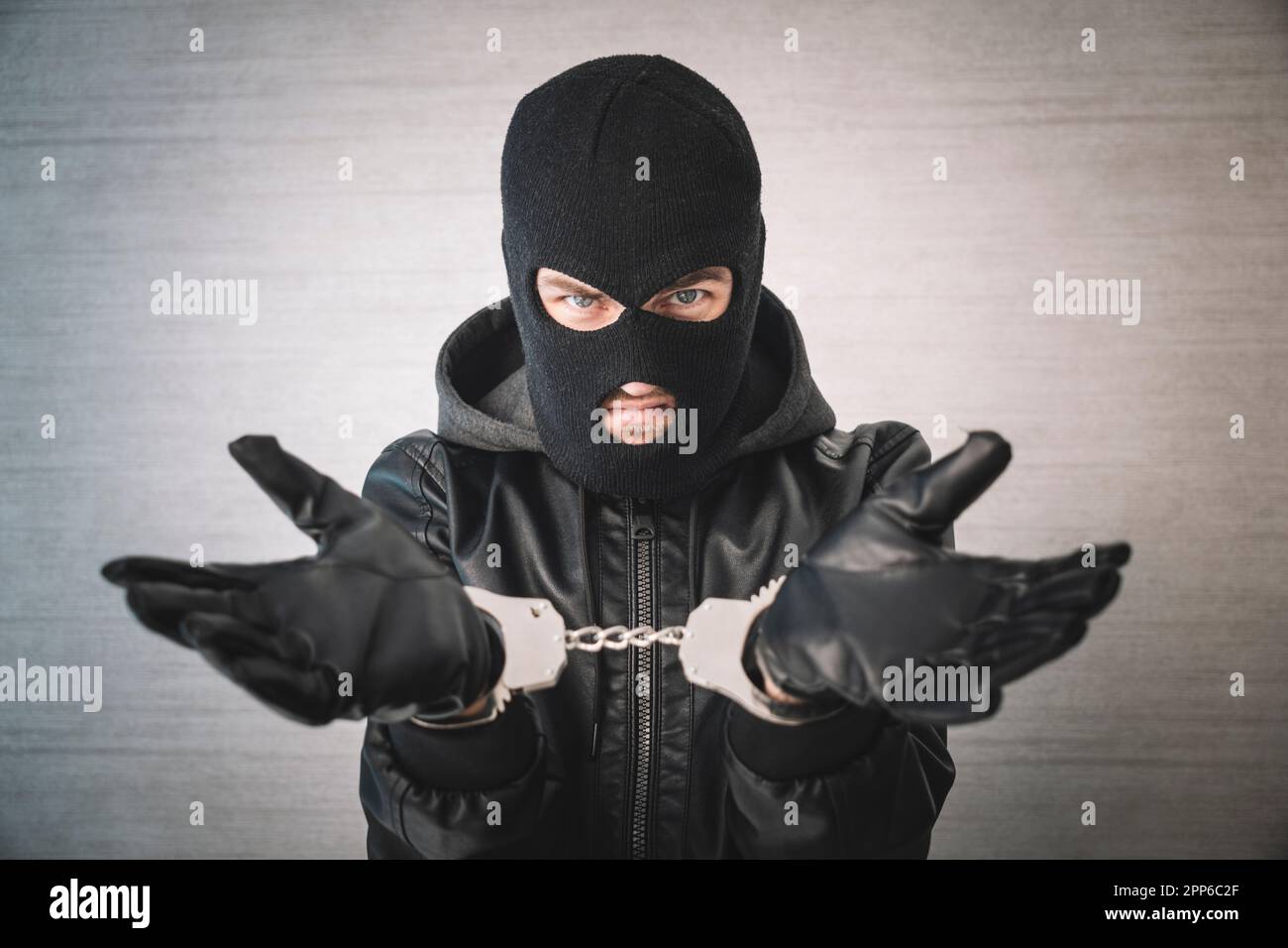 a dangerous criminal is handcuffed in prison for interrogation. A repentant sad man with his head on the table. Arrest of a bandit. Stock Photo