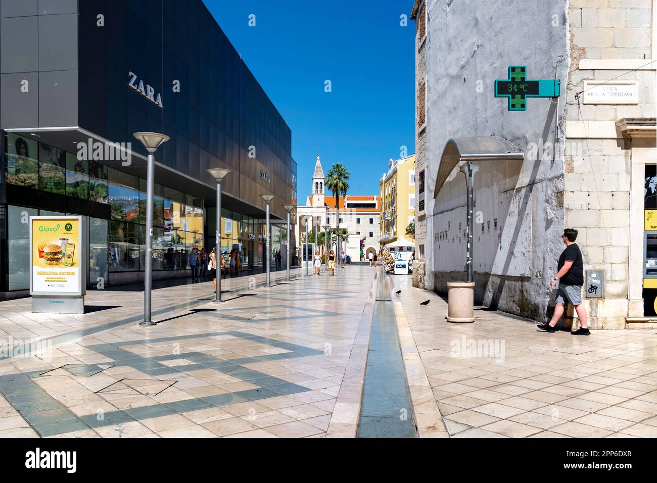 A pedestrian walks down a street with modern shops. Split, Croatia. Stock Photo