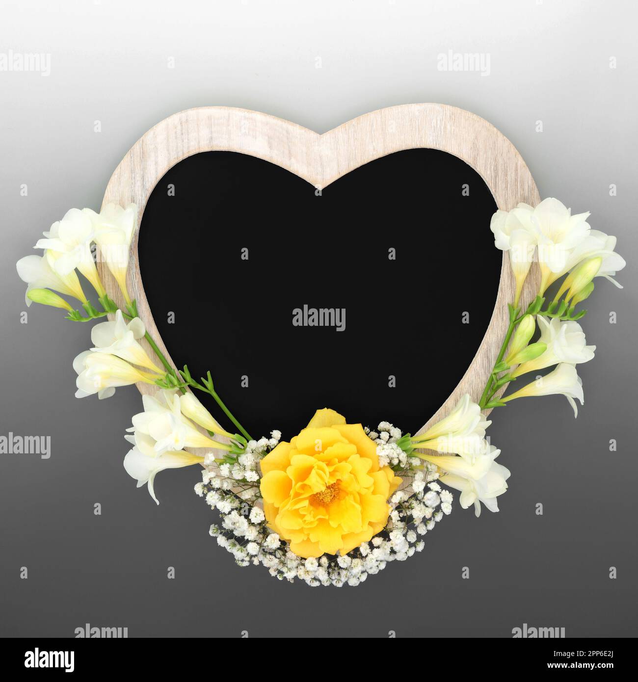 Heart shaped rustic wooden frame with chalkboard and flowers. Suitable for In Memoriam card, funeral invitation, mourning, RIP concept. Stock Photo