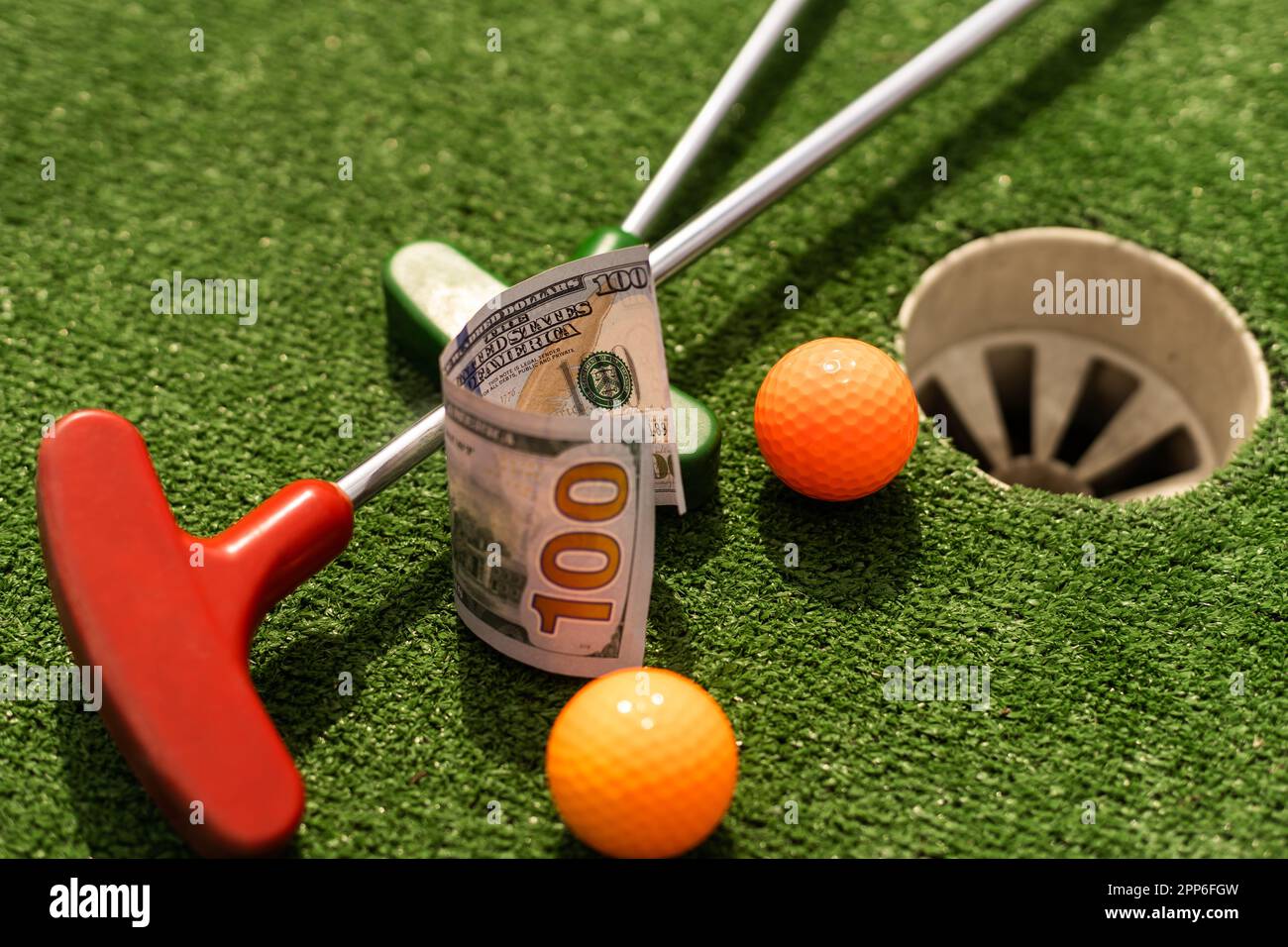 Mini Golf club, ball and money on the artificial grass Stock Photo