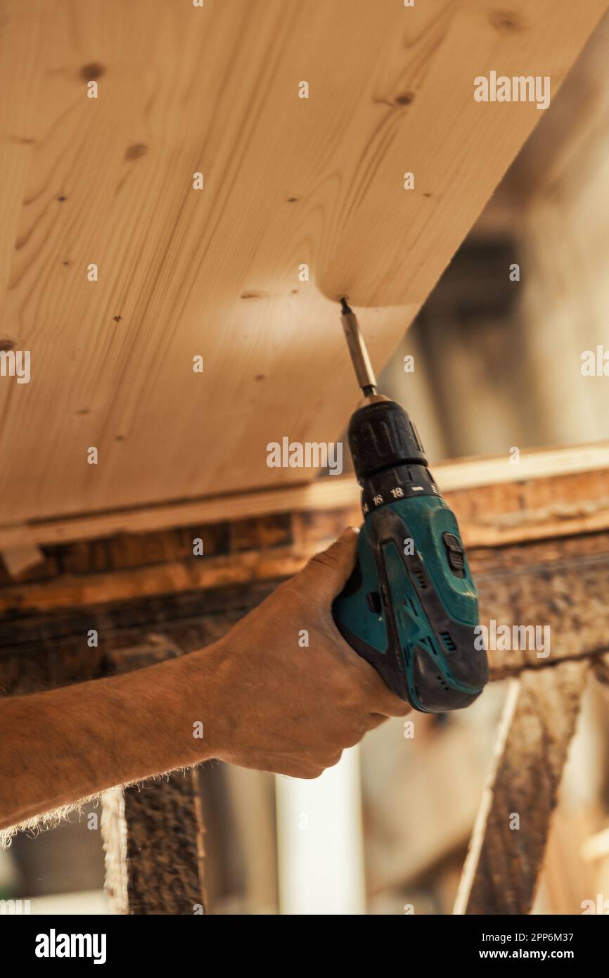 Carpenter's hand using an electric screwdriver with illuminated tip