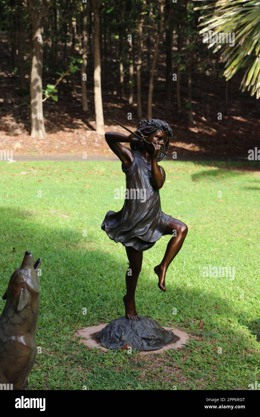 A bronze statues of a girl playing playing a flute and a dog howling in