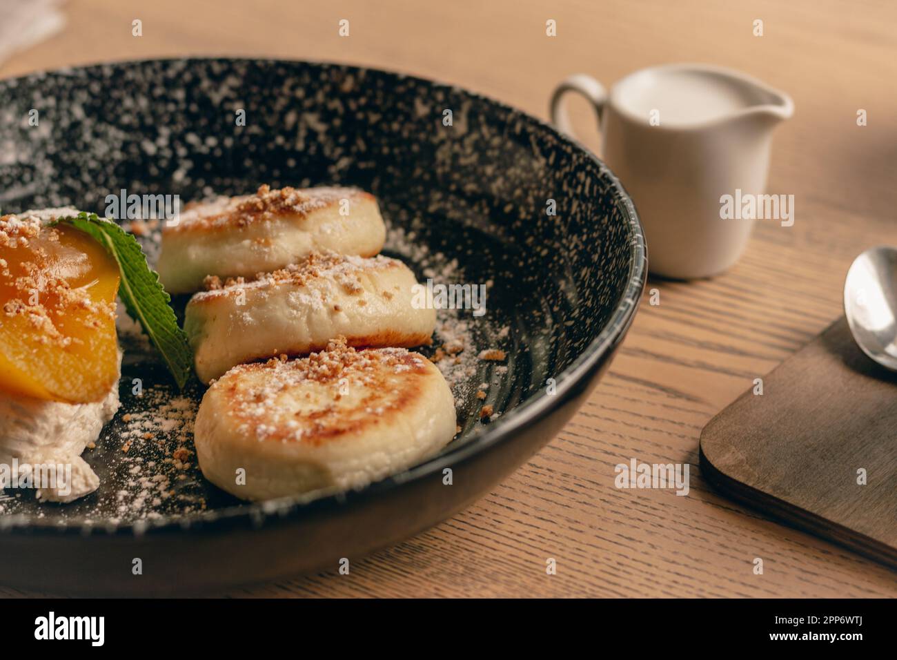 Syrniki with caramel pear and milk cup. Curd cottage pancakes with milk. Delicious breakfast in restaurant. Cheese pancakes close-up. Restaurant menu. Stock Photo