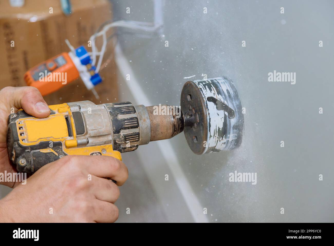 Installing electrical wires in wall by drilling holes in drywall Stock