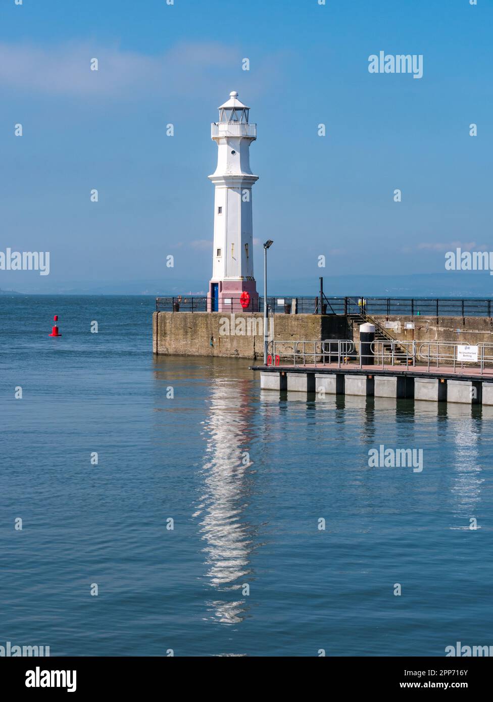 Lighthouse reflected in water on sunny day at Newhaven Harbour, Edinburgh, Scotland, UK Stock Photo