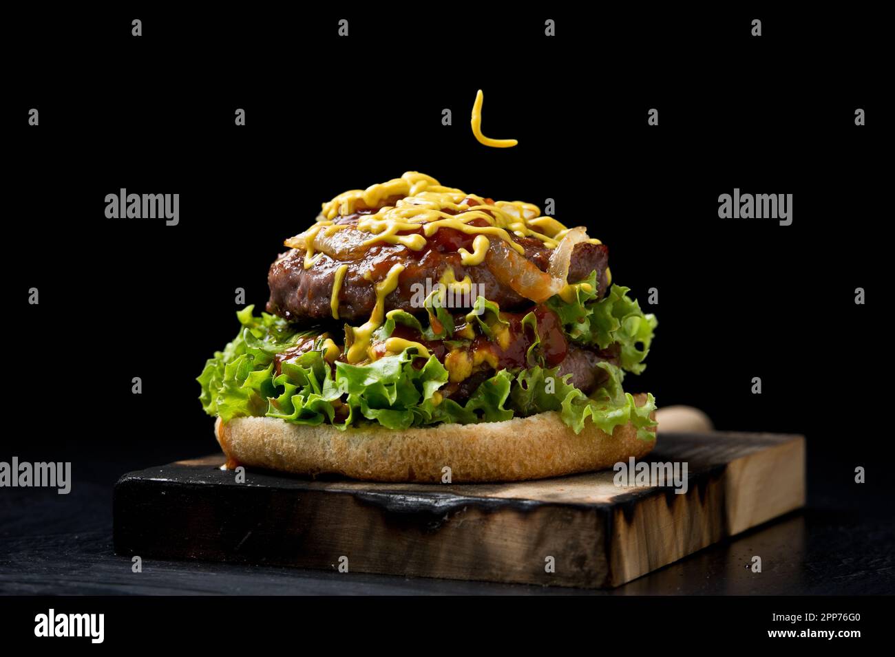 Beef burger. With mustard and ketchup, lettuce and onion. Black