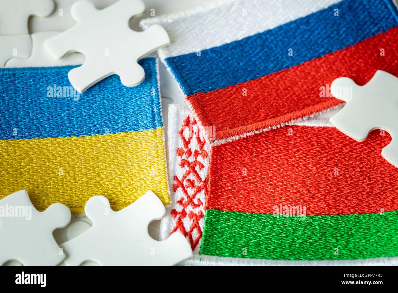 The flag of Belarus and the background of the flags of Russia and Ukraine among the jigsaw puzzles, the concept of the political situation, the role o Stock Photo