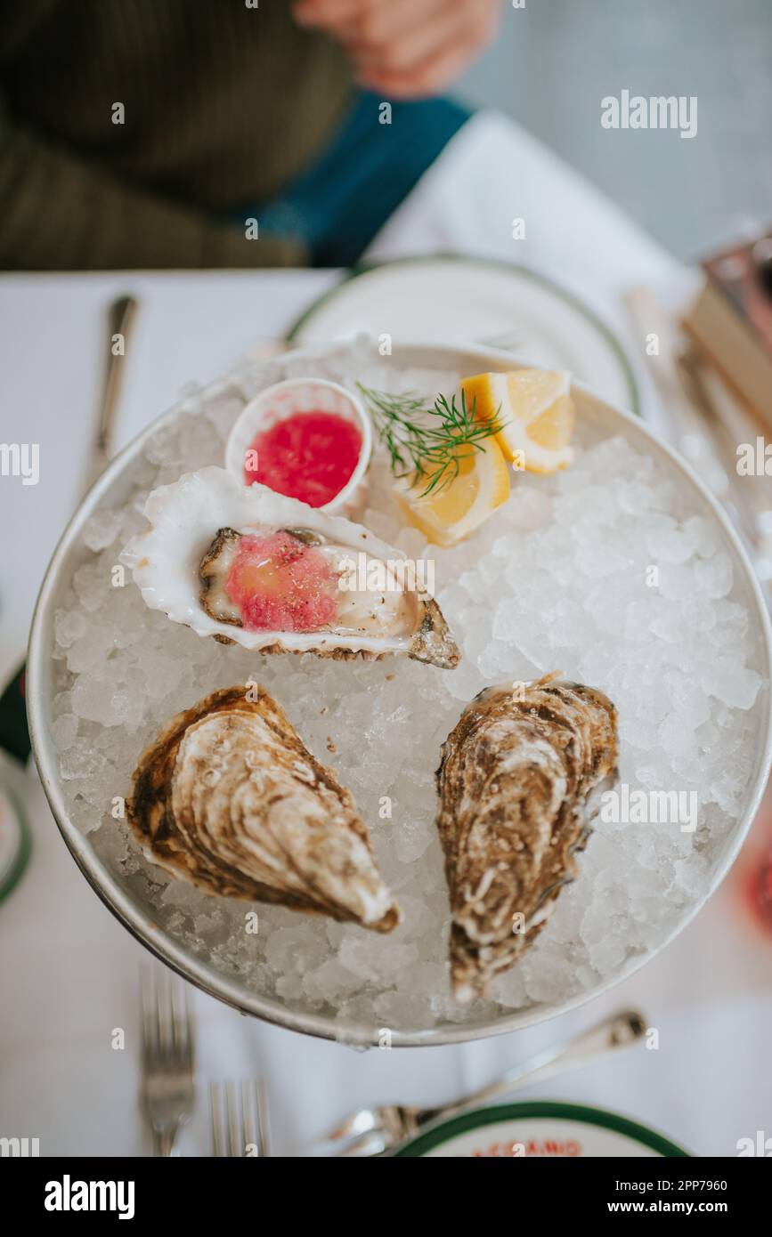 The picture captures a scene of luxury dining in Rome, where a platter of freshly shucked oysters is presented on a bed of ice Stock Photo