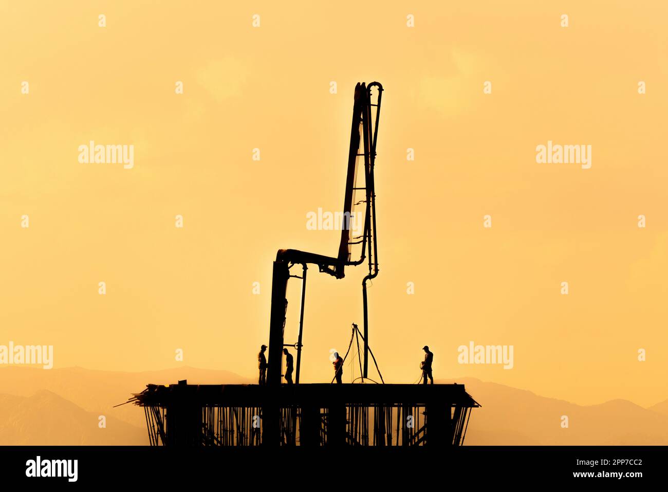 Workers pouring concrete at a construction site. Reverse light, silhouette Stock Photo