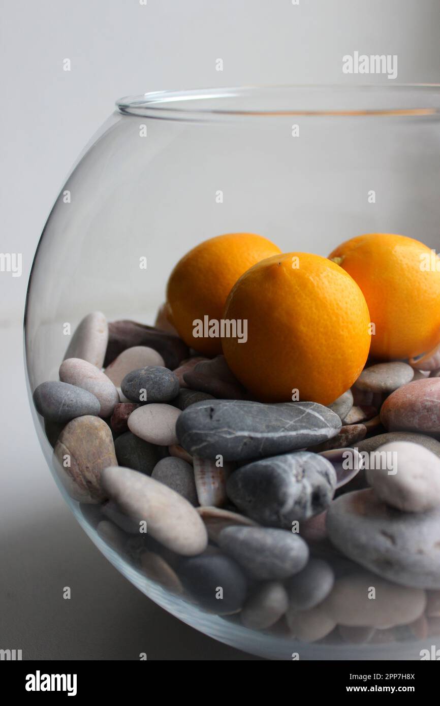 Side View Of Half Filled Of Smooth Pebbles Glass Vase With Ripe Yellow