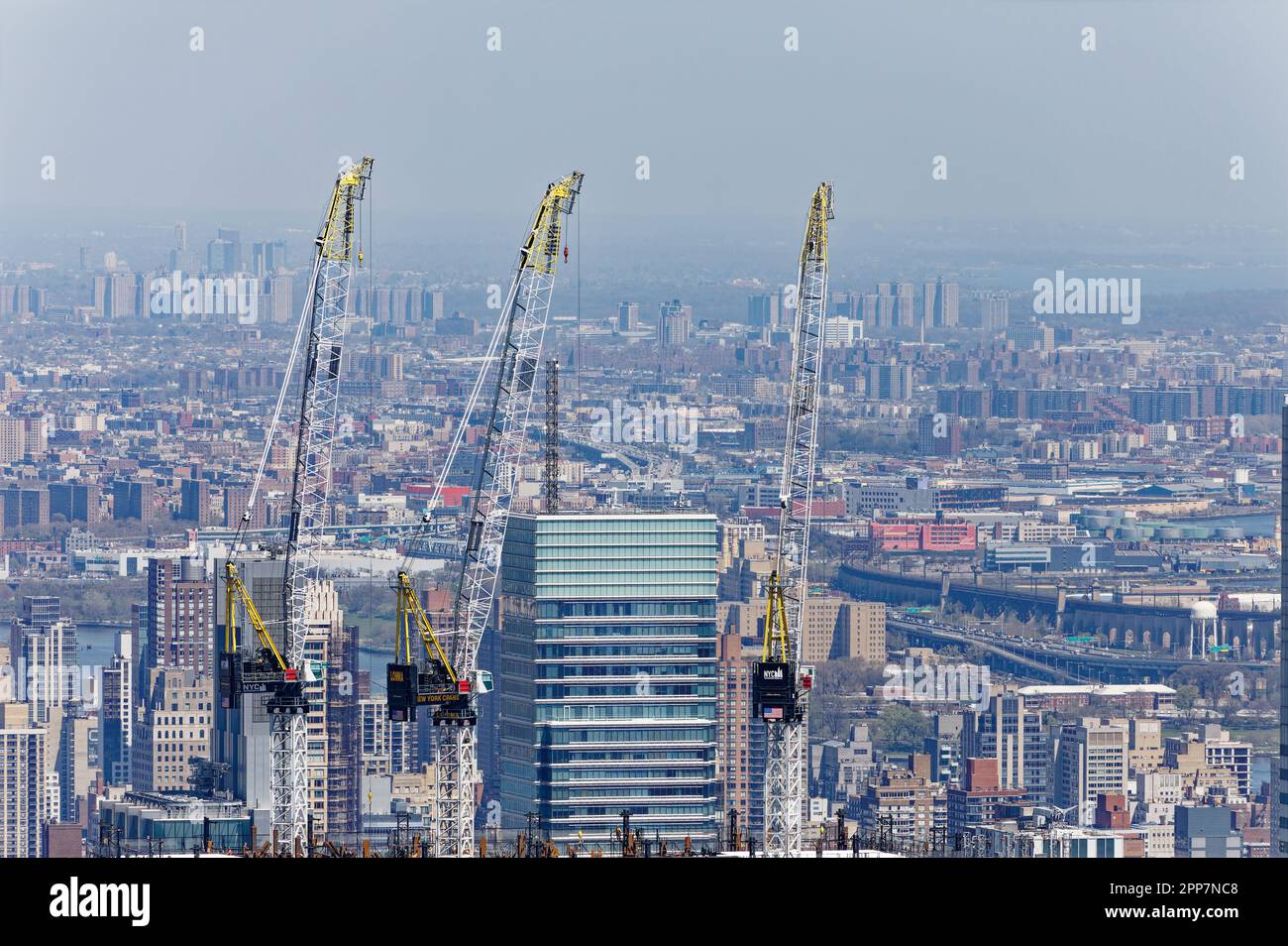The glass crown of Bloomberg Tower, 731 Lexington Avenue, seems besieged by nearby construction cranes in Manhattan’s Midtown East section. Stock Photo