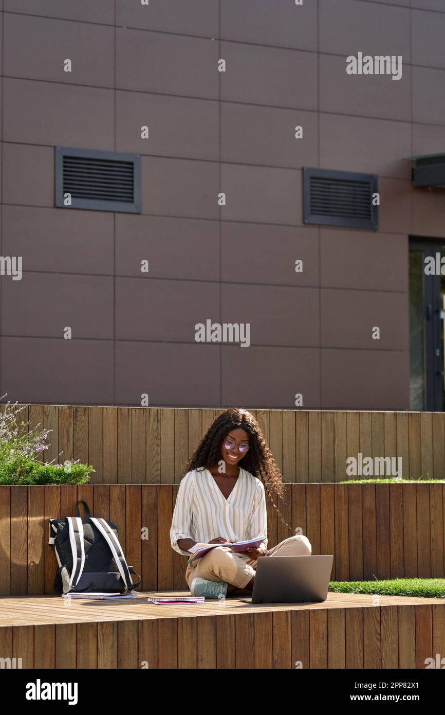 African young woman student learning online using laptop outside campus ...
