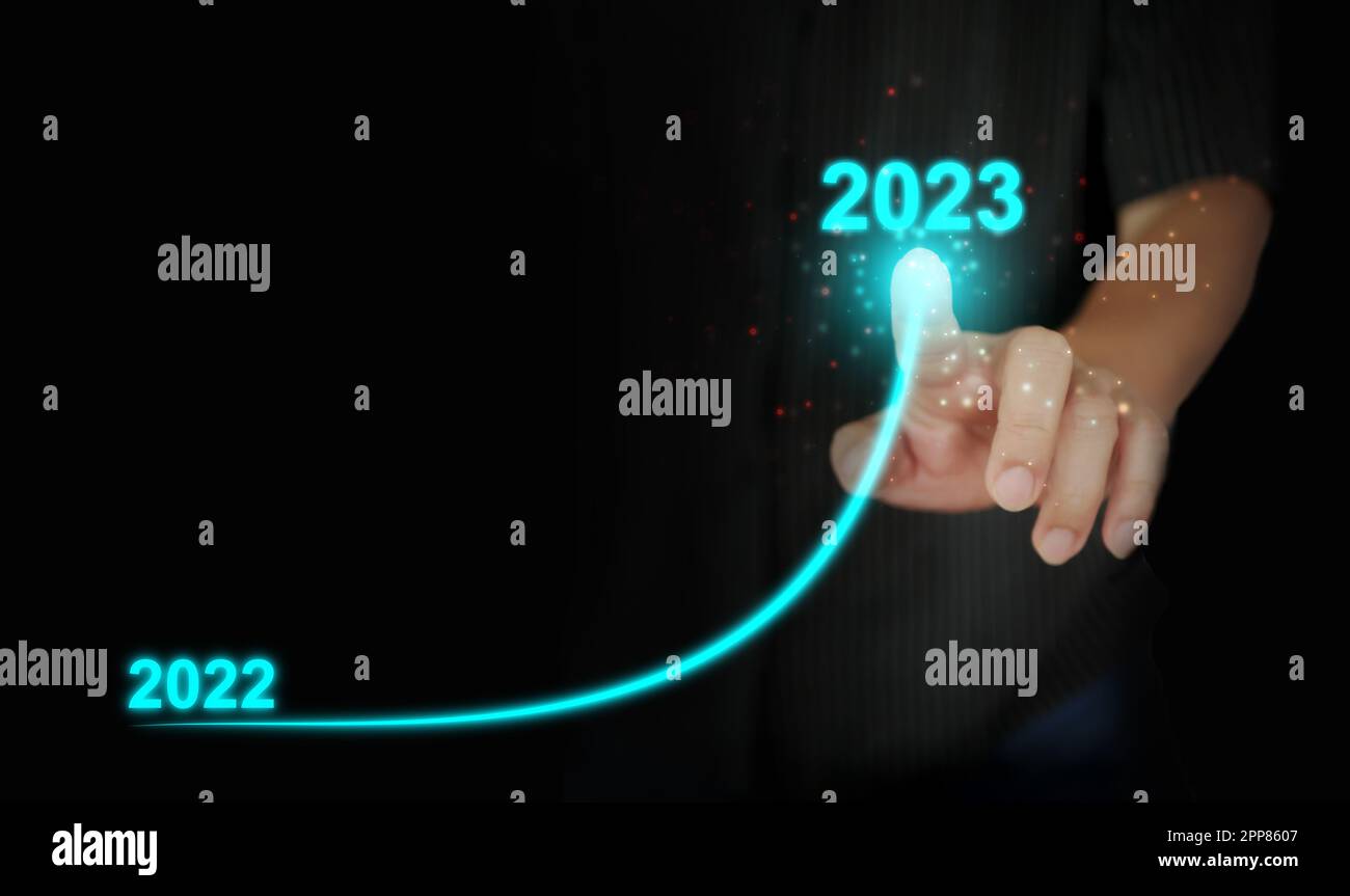 A man's finger draws an upwards curved line from 2022 to 2023. New Year, Christmas, start-up, new business, setting a personal goal Stock Photo