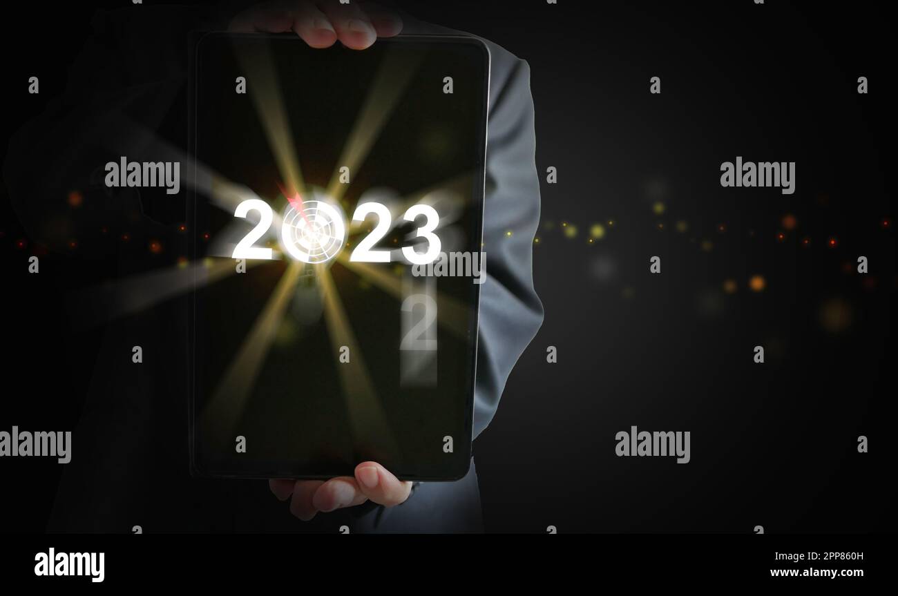 Businessman's hands holding a tablet with the year changing from 2022 to 2023. Time to start new year, business, project, path, goal, or life. Stock Photo