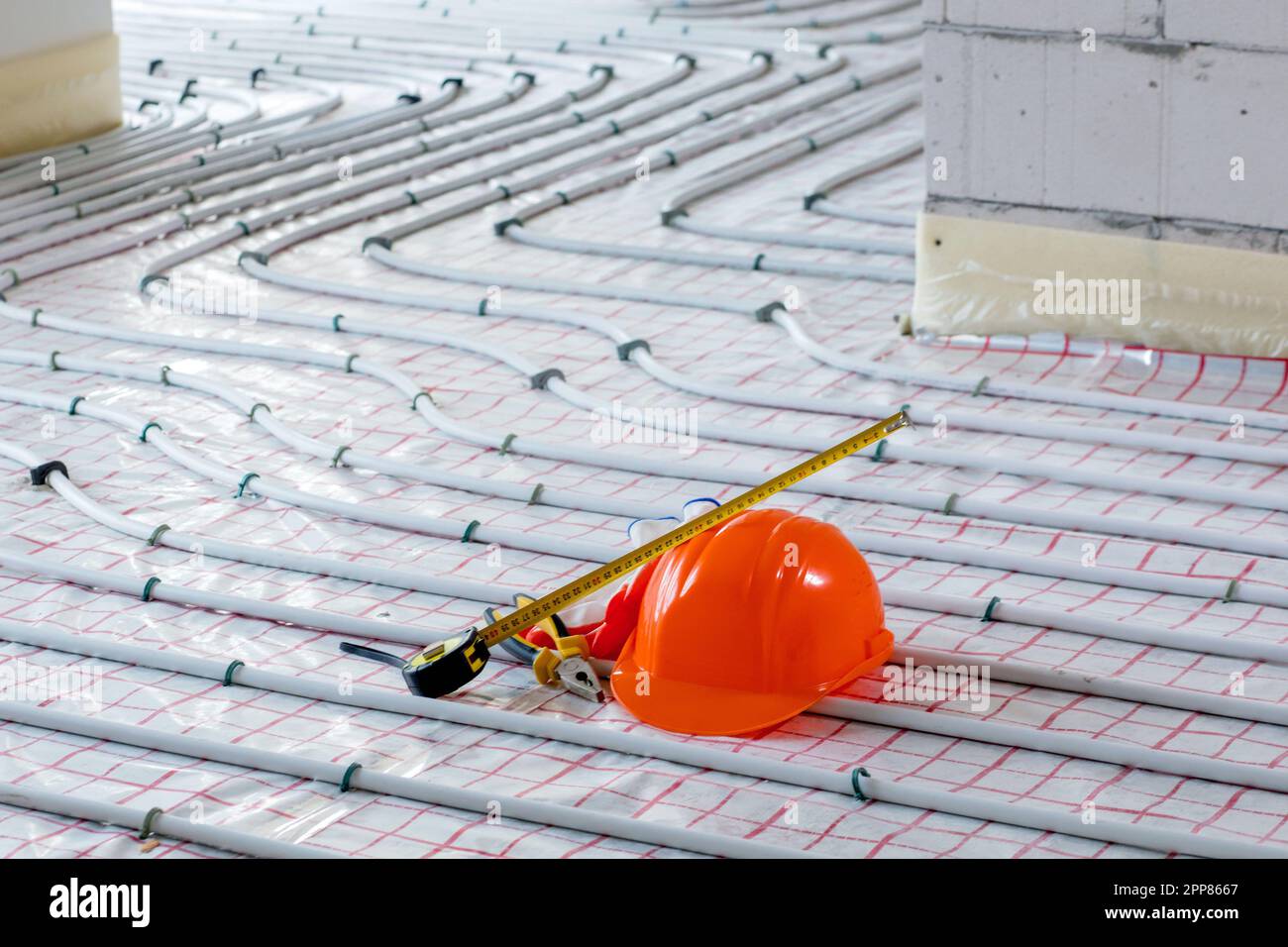 Tools for repair hard hat, plier, glove on warm floor. Installation of