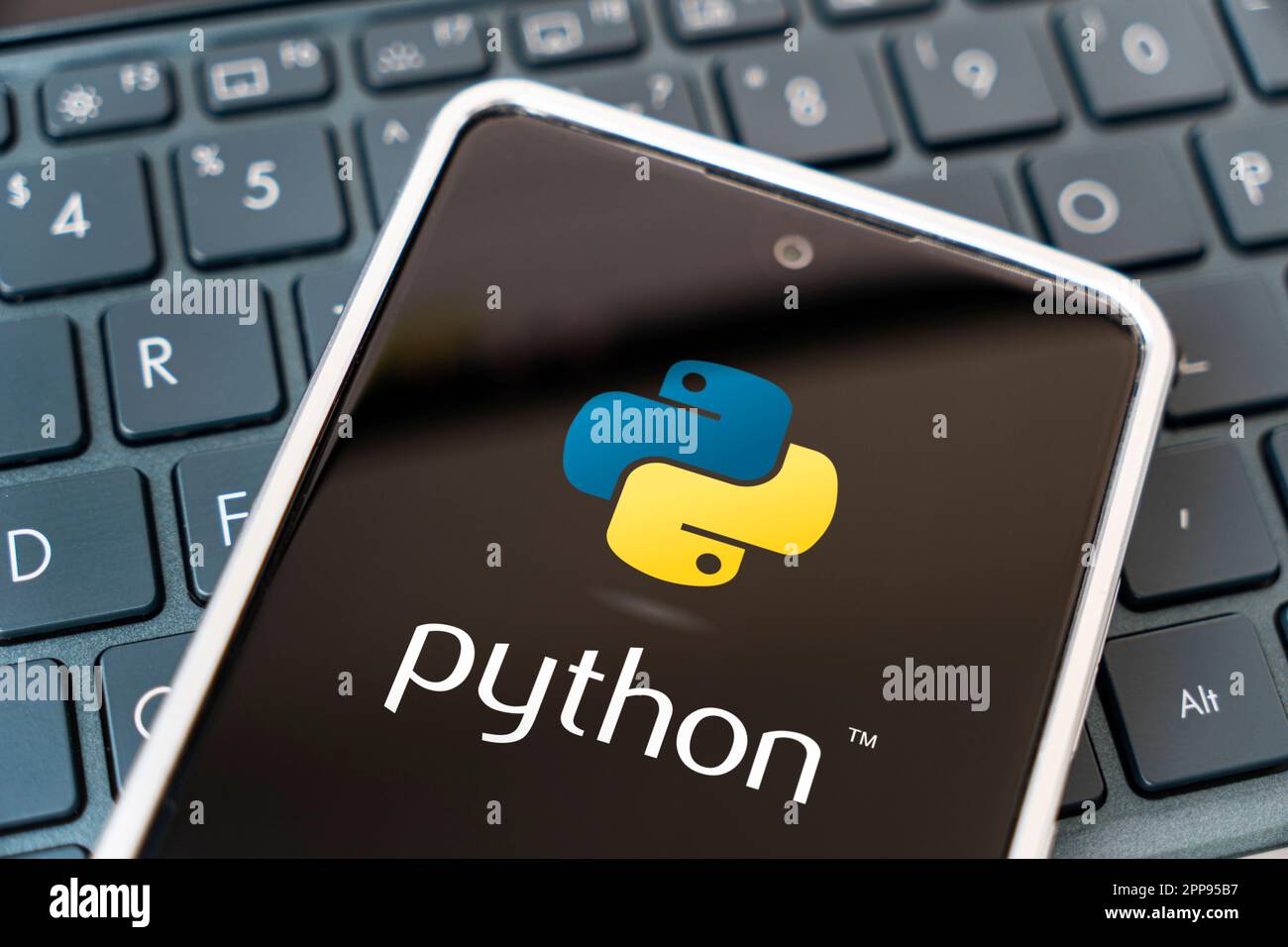 Programming language for mobile development, concept. Smartphone on the laptop keyboard. logo python on the mobile phone screen. Barnaul. Russia March Stock Photo