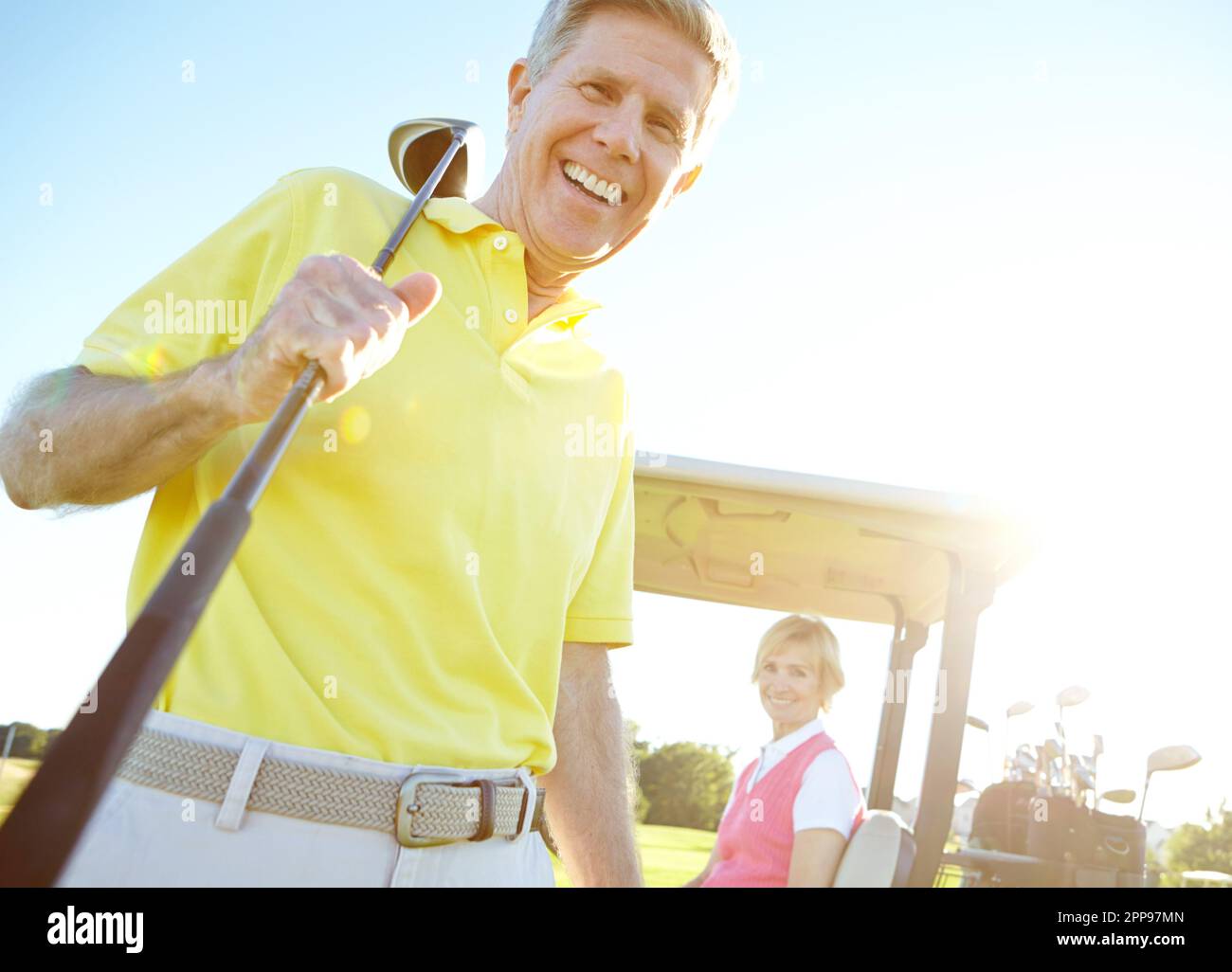 Amateur golfers. Low angle shot of a handsome older golfer standing in front of a golf cart with his golfing buddy behind the wheel. Stock Photo