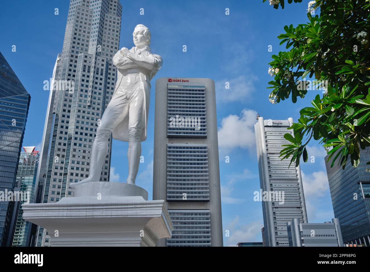 A statue of Sir Stamford Raffles at Raffles' Landing Pier, Boat Quay, Singapore River, Singapore; b/g: the skyline of the Singapore business district Stock Photo