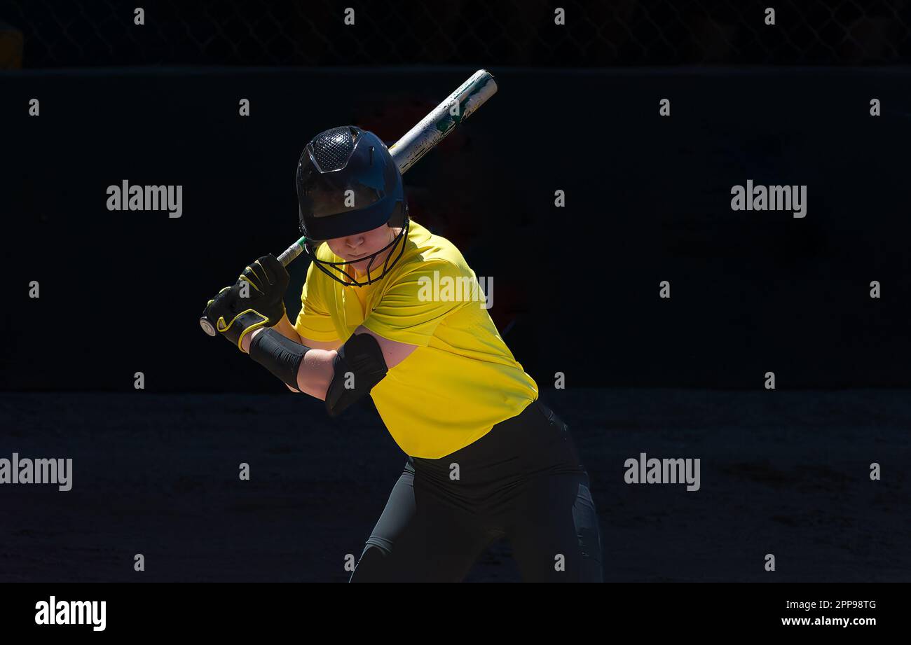 A Baseball Softball Player Is Swinging And Hitting The Ball Stock Photo
