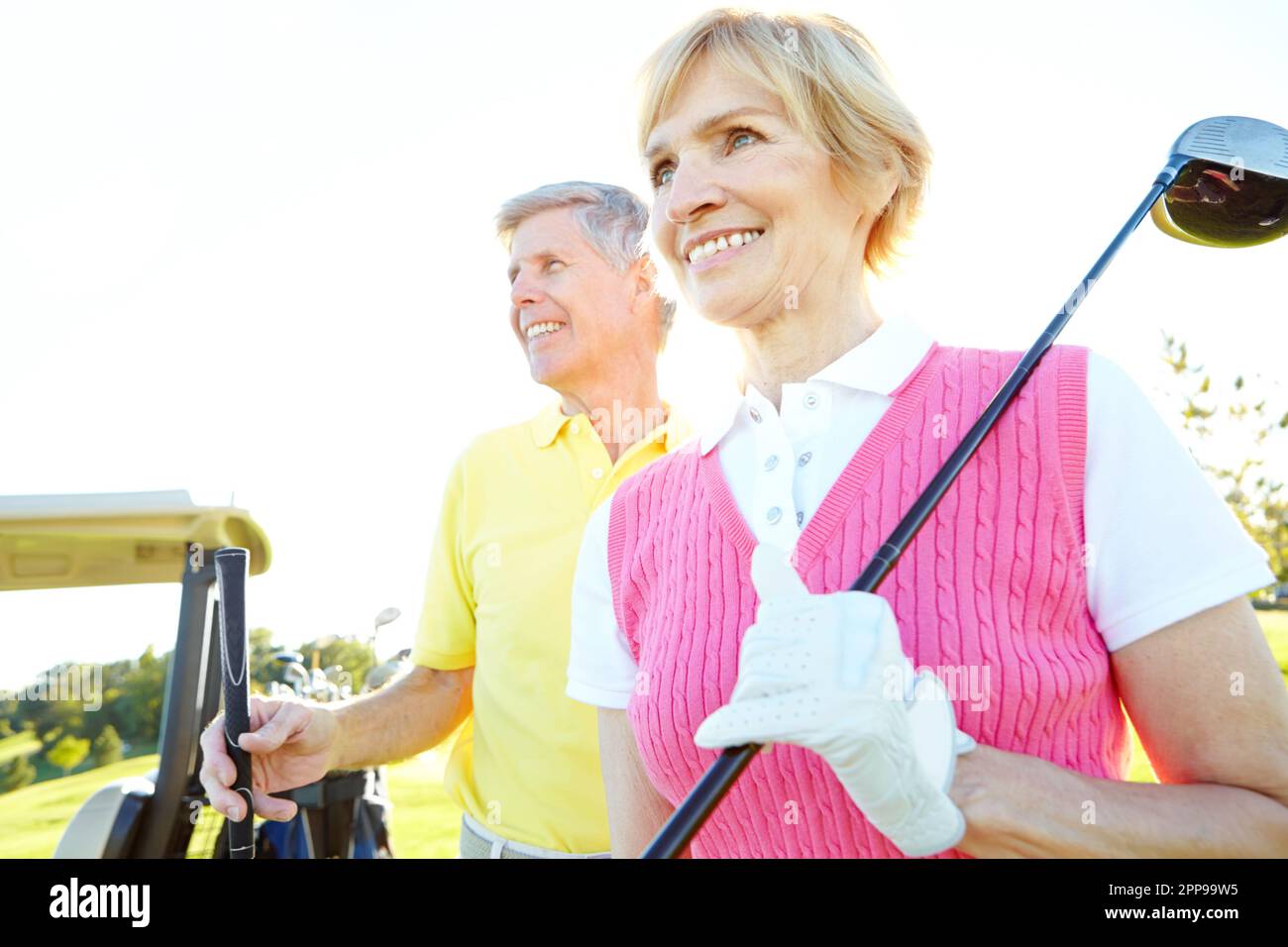Enjoying their golf day. Attractive elderly couple with their golf clubs over their shoulders. Stock Photo