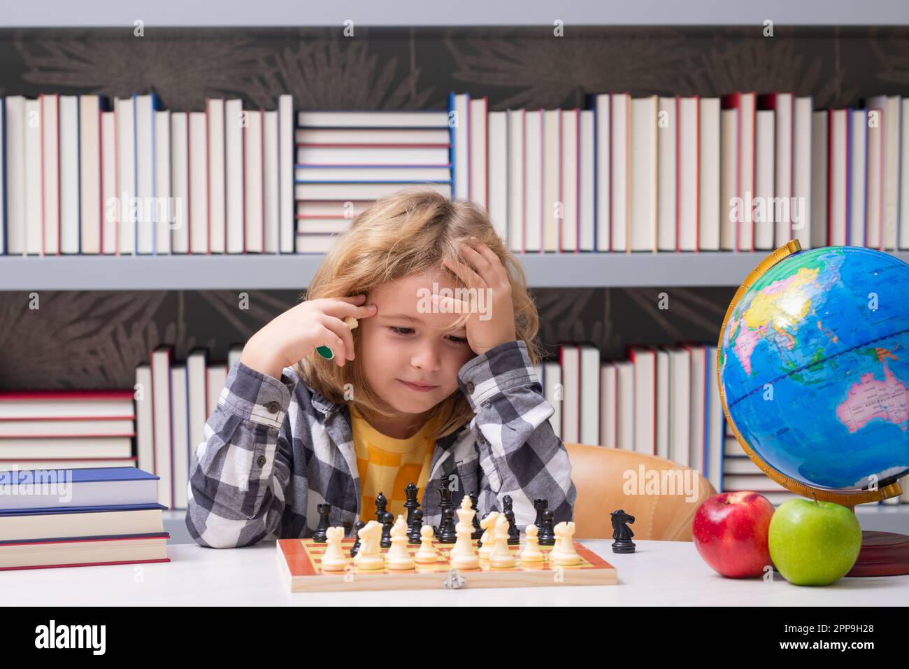 Pupil kid thinking about his next move in a game of chess. Concentrated  little boy sitting at the table and playing chess Stock Photo - Alamy