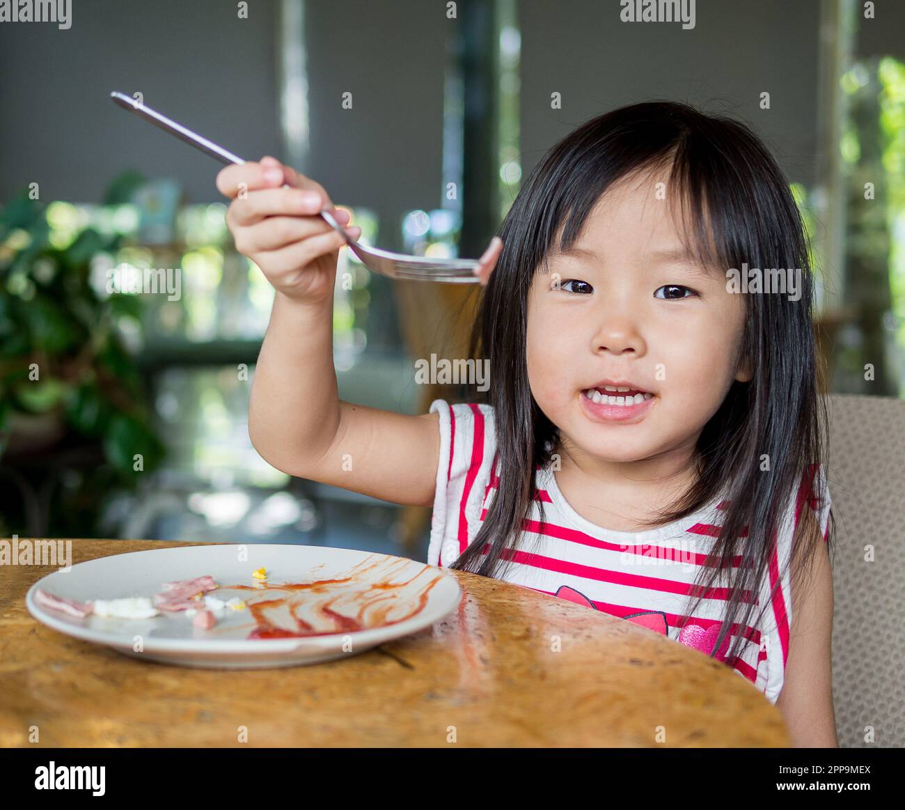 Asian girl child eating american breakfast Stock Photo - Alamy