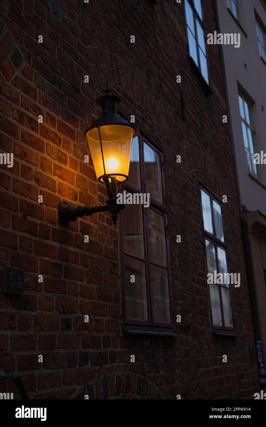 Late evening photo of street lamp mounted on a brick wall Stock Photo ...