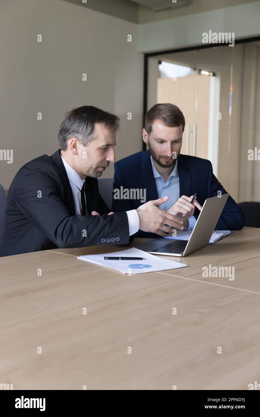 Two serious business colleagues men using laptop at work table Stock Photo