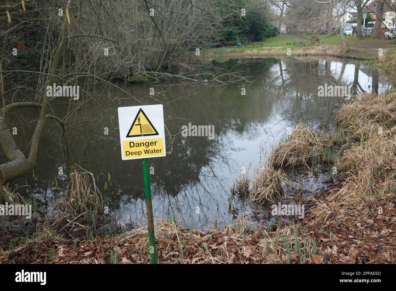 A warning sign advising people to take care near a deep water pond in the village of Letchmore Heath Hertfordshire. Watch your kids!! Stock Photo