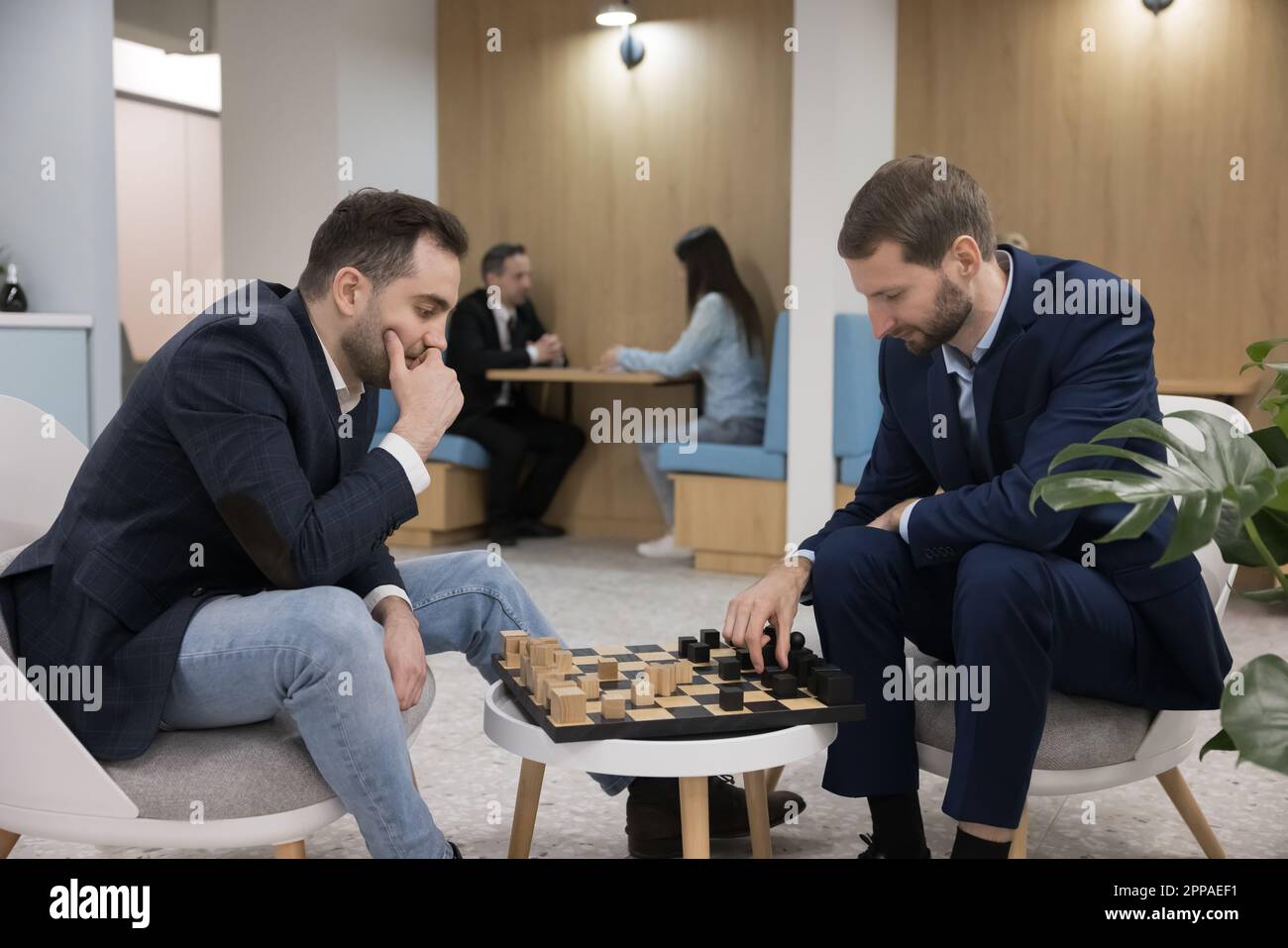 Two men sitting indoors playing a game of chess in hotel lounge Stock Photo  - Alamy