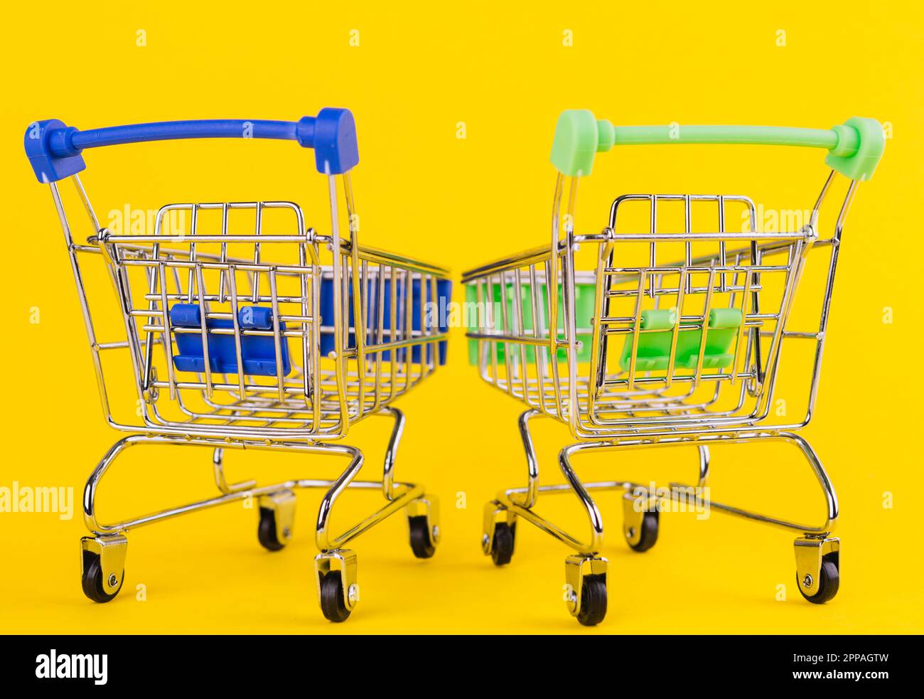 Two miniature green blue shopping cart yellow background Stock Photo