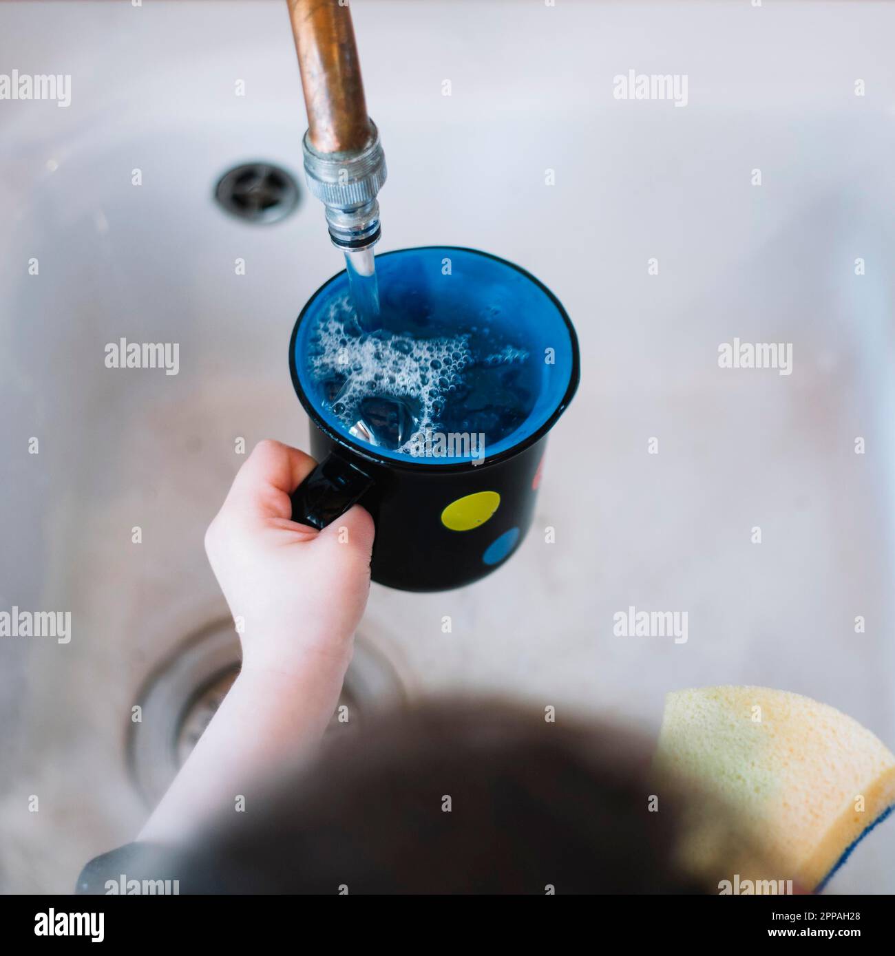 Girl s hand filling cup with water Stock Photo