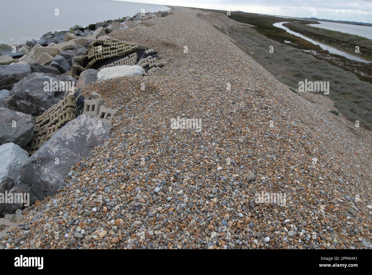 Erosion of narrow shingle ridge above flood defences at Sudbourne Beach, a natural barrier between the North Sea & Alde Ore Estuary. 19th March 2023. Stock Photo