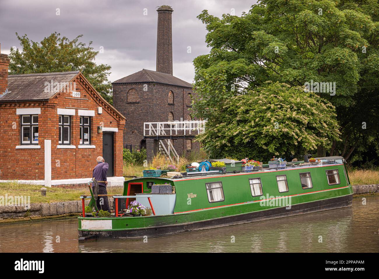 A narrowboat at Sutton Stop with the old engine house in the background at Hawkesbury Junction where the Coventry Canal meets the Oxford Canal. Stock Photo