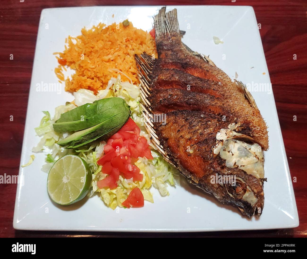 Pescado Frito, a Mexican dish with fried tilapia, yellow rice, salad
