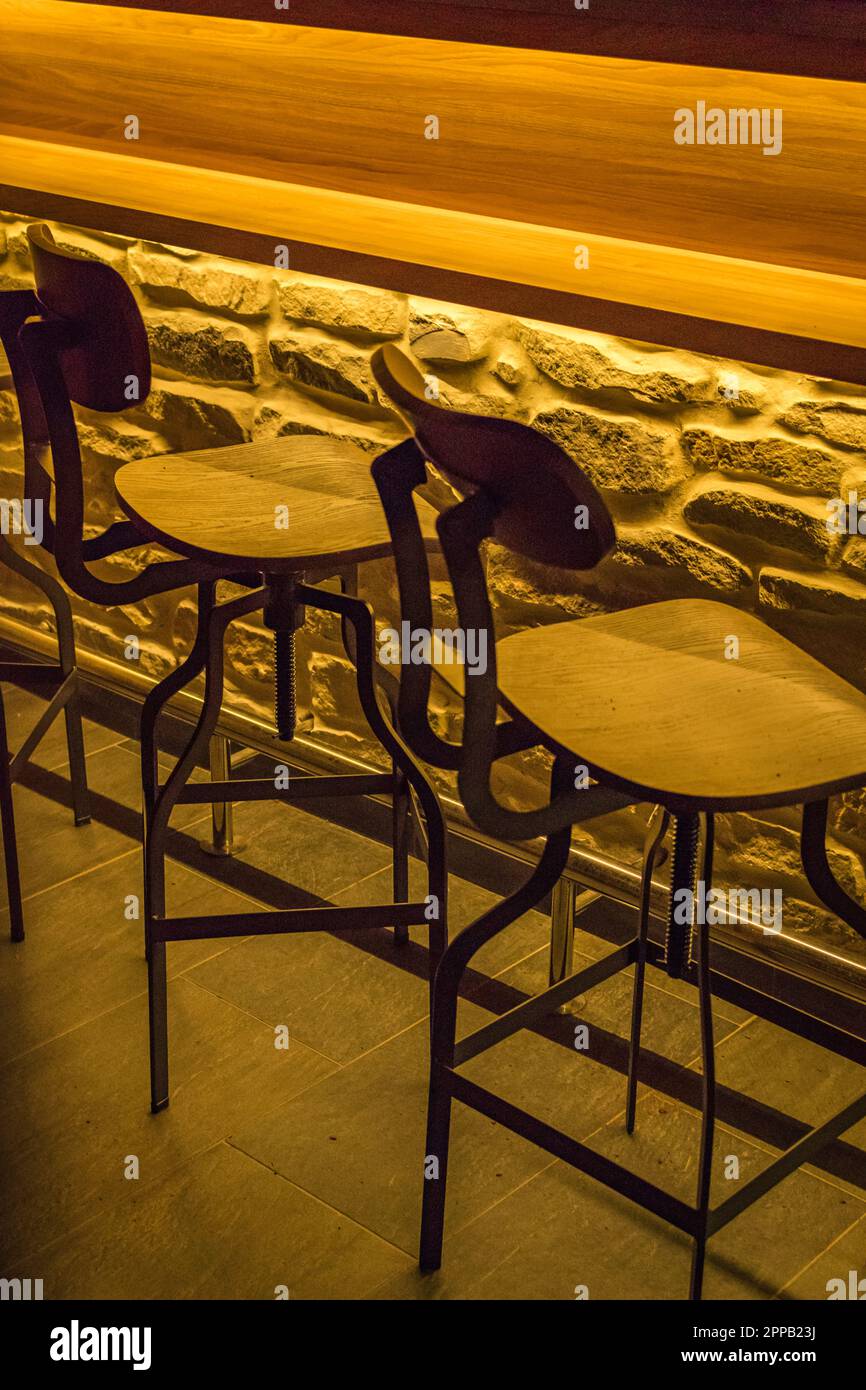 Bar stools chairs in a bar with artificial light and brick covered bar